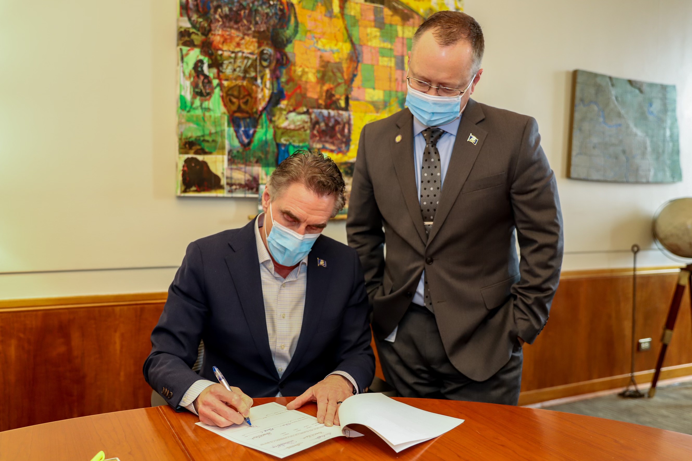 Governor Burgum signs House Bill 1052 as Lieutenant Governor Sanford looks on